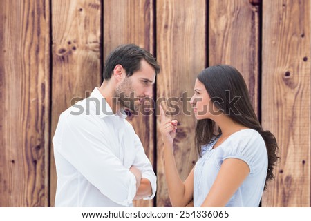 Angry couple facing off during argument against wooden planks background
