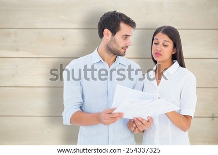 Attractive young couple reading their bills against bleached wooden planks background