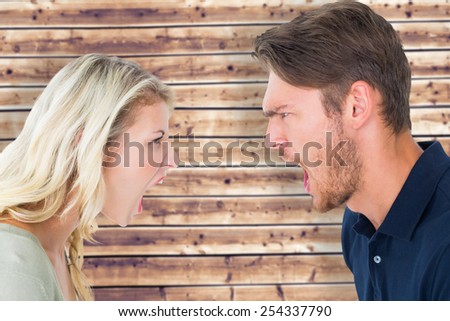 Angry couple shouting during argument against wooden planks background