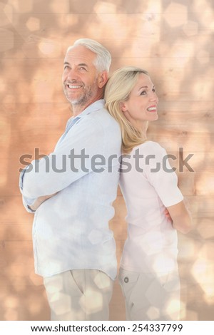 Smiling couple standing leaning backs together against light glowing dots design pattern