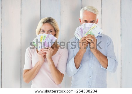 Happy couple flashing their cash against wooden planks