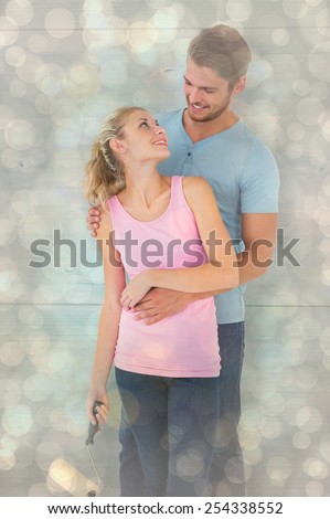 Young couple painting with roller against light glowing dots design pattern