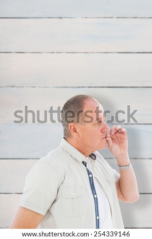 Older man holding hand to mouth for silence against wooden planks