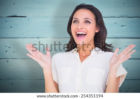Surprised brunette with hands up against painted blue wooden planks