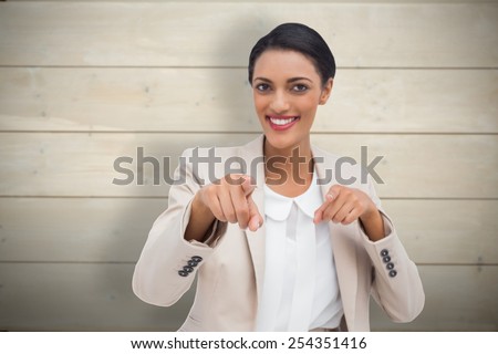 Smiling businesswoman pointing at the camera against bleached wooden planks background