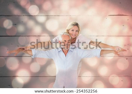 Smiling couple posing with arms out against light circles on black background