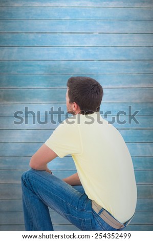 Man crouching and looking up against wooden planks