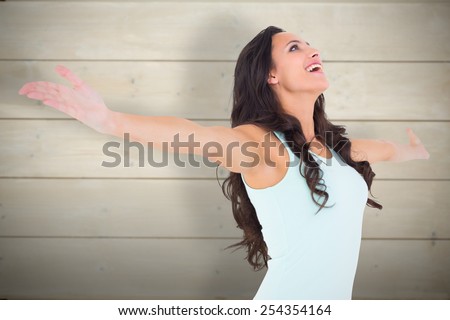 Carefree brunette with arms out against bleached wooden planks background
