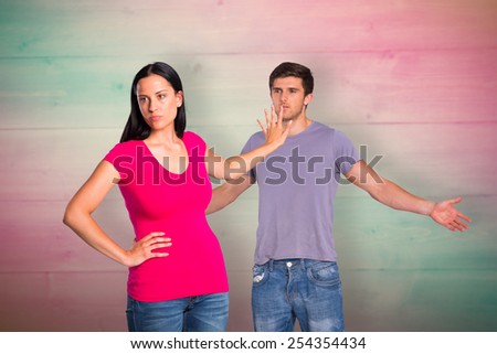 Young couple having an argument against pink and green planks