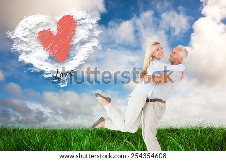 Man picking up his partner while hugging here against cloud heart