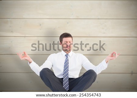 Businessman meditating in lotus pose against bleached wooden planks background