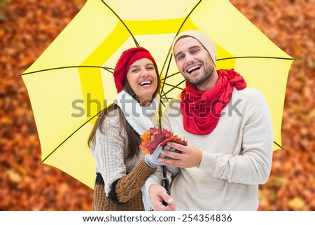 Autumn couple holding umbrella against autumn leaves on the ground