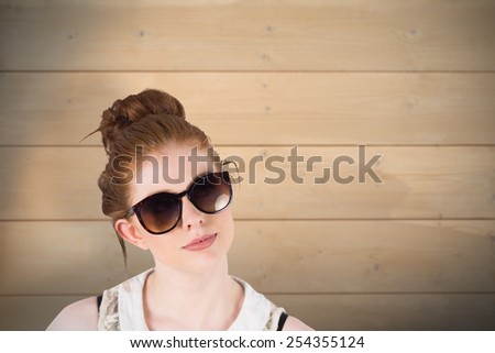 Hipster redhead wearing large sunglasses against bleached wooden planks background