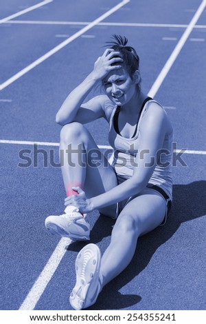 Runner with ankle injury sitting on track