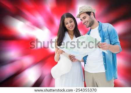 Happy hipster couple looking at map against valentines heart pattern