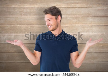 Handsome young man holding his hands out against wooden surface with planks