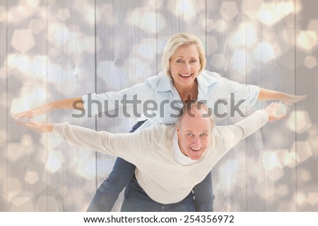 Happy mature couple having fun against light glowing dots design pattern