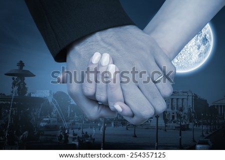 Newlyweds holding hands close up against large moon over city