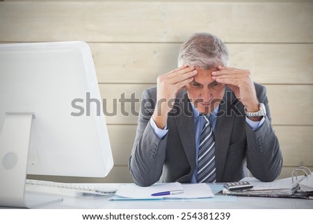 Worried businessman at desk against bleached wooden planks background