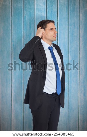 Thinking businessman scratching head against wooden planks