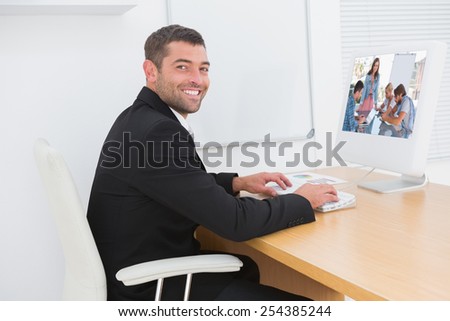 Team having meeting with one woman smiling at camera against smiling businessman working at a desk