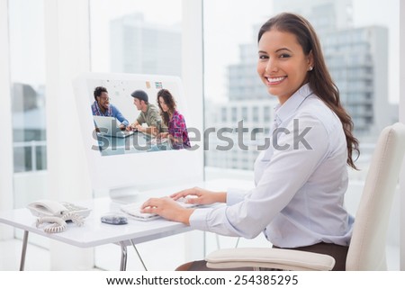 Creative team working together against smiling businesswoman working at her desk
