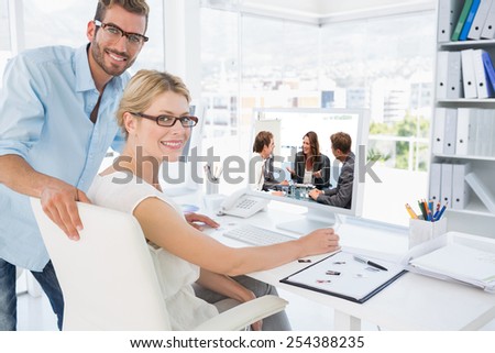 Attractive businesswoman laughing with her team against side view portrait of photo editors working on computer