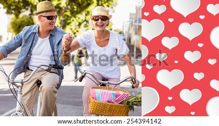 Happy mature couple going for a bike ride in the city against heart pattern