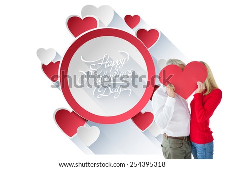 Couple embracing and holding heart over faces against happy valentines day