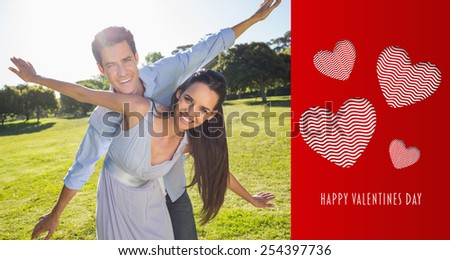 Happy couple with arms outstretched at park against cute valentines message