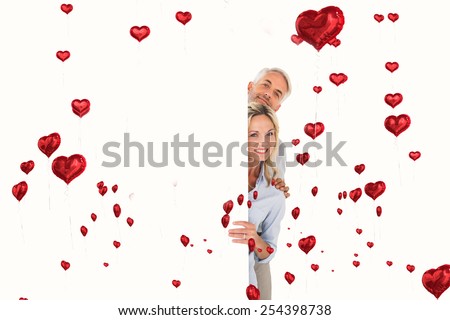Happy couple showing large poster against red heart balloons floating
