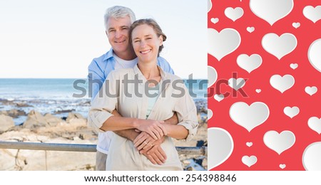 Happy casual couple hugging by the coast against heart pattern