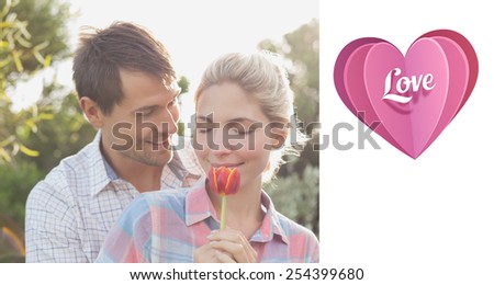 Young couple holding a flower in park against love heart