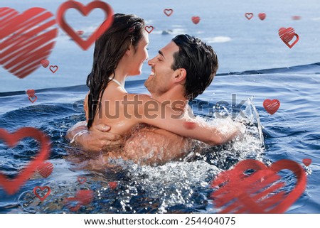 Joyful couple cuddling each other against love heart pattern