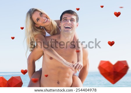 Laughing man giving his pretty girlfriend a piggy back smiling against hearts