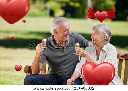 Senior couple eating an ice cream on a bench against hearts