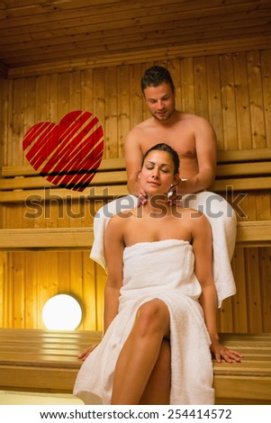 Man giving his girlfriend a neck massage in sauna against red heart