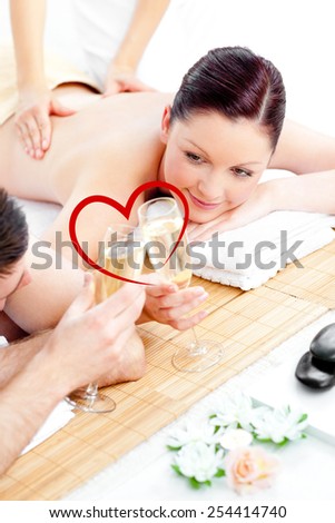Young couple enjoying a back massage and drinking champagne against heart