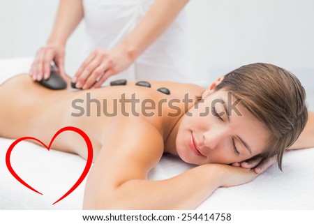 Beautiful woman receiving stone massage at spa center against heart