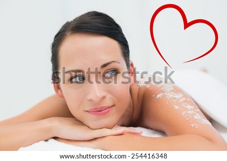 Peaceful brunette lying with salt scrub on back against heart