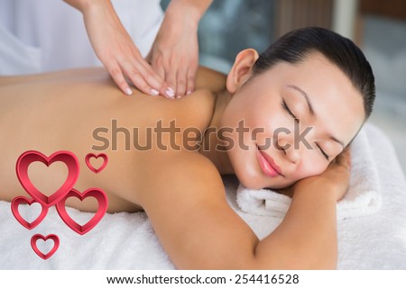 Content brunette getting a back massage against pink hearts