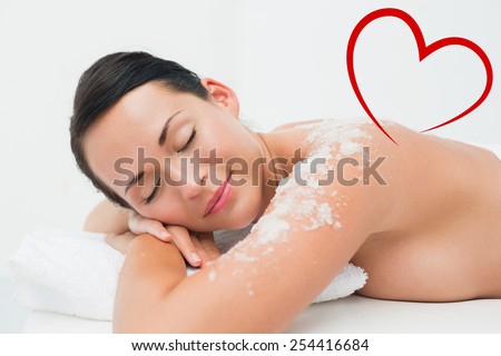 Peaceful brunette lying with salt scrub on shoulders against heart