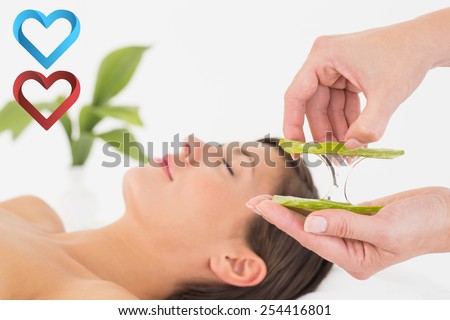 Attractive young woman receiving aloe vera massage at spa center against hearts