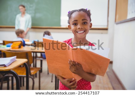 Cute pupils smiling at camera in classroom at the elementary school