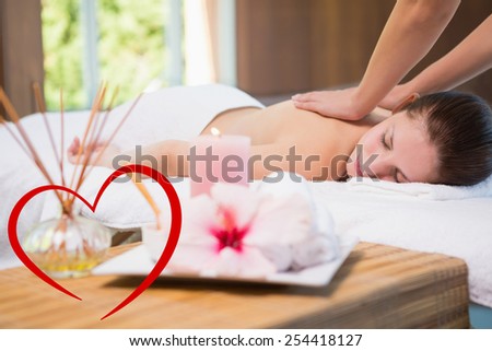 Attractive woman receiving back massage at spa center against heart