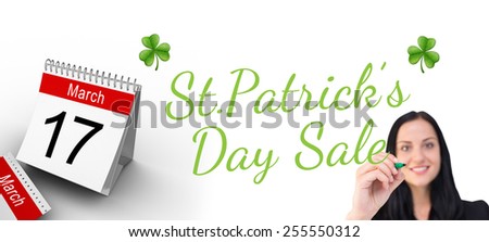 Pretty businesswoman writing with marker against shamrock