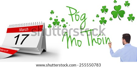 Rear view of a businessman writing with marker against shamrocks