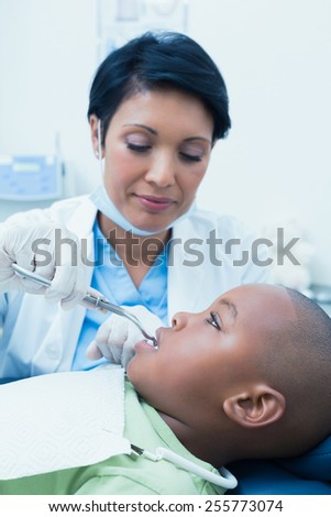 Close up of female dentist examining boys teeth in the dentists chair
