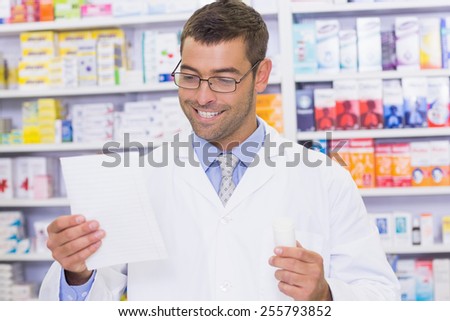 Happy pharmacist looking at prescription at the hospital pharmacy