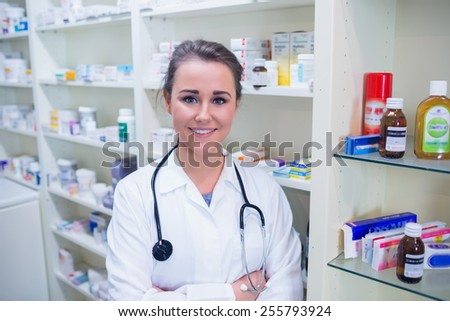 Student in lab coat with stethoscope and arms crossed in the pharmacy